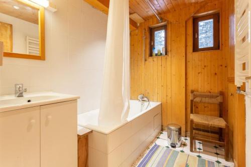 een badkamer met een bad, een wastafel en een spiegel bij Chalet Robaumont - Grand chalet familial proche du centre et des pistes in Courchevel
