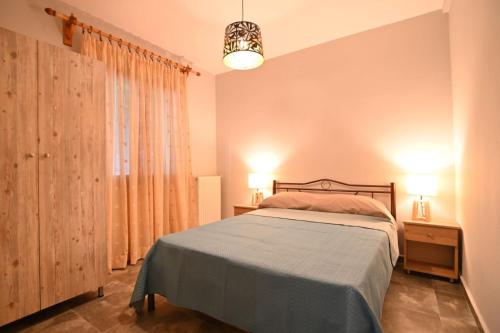 a bedroom with a bed and two lamps and a window at Nihtolouloudo house in Nea Vrasna