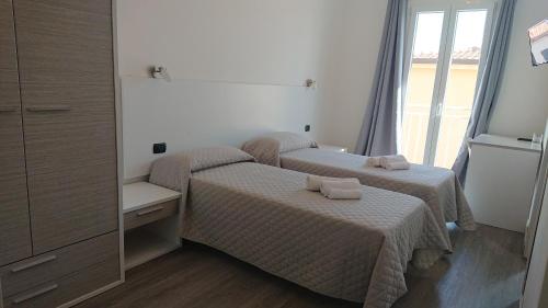 two beds in a small room with a window at Hotel Ogliastra in Lotzorai