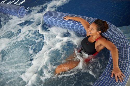 a woman laying on a board in a swimming pool at Hilton at St George's Park in Burton upon Trent
