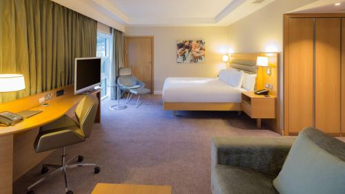 a hotel room with a bed and a desk with a computer at Hilton at St George's Park in Burton upon Trent