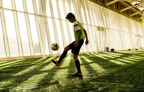 a young man kicking a soccer ball in a building at Hilton at St George's Park in Burton upon Trent