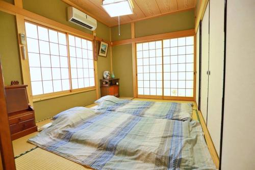 a large bed in a room with three windows at FOREST HOUSE NIKKO in Nikko