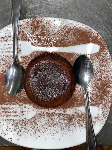 a chocolate cake on a plate with two spoons at Albergo Alla Posta in Anduins