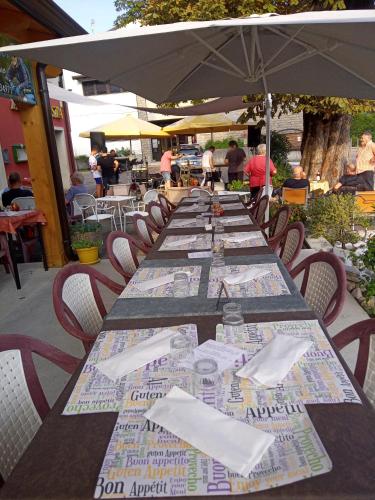 a long wooden table with chairs and an umbrella at Albergo Alla Posta in Anduins