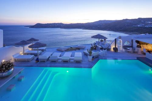 una piscina con sillas y sombrillas y el océano en Smy Mykonos Suites & Villas - ex Greco Philia, en Playa de Elia