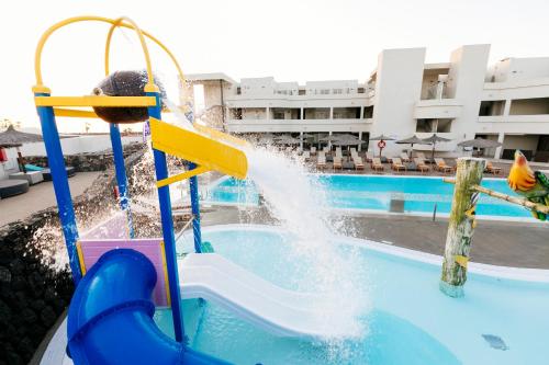 un niño jugando en un tobogán de agua en una piscina en HD Beach Resort en Costa Teguise