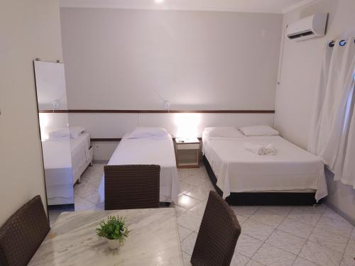 um quarto com duas camas e uma mesa e cadeiras em Pousada Aruamar em Aracaju
