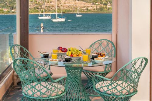 een tafel met fruit op een balkon met uitzicht op het water bij Pink Panther Maisonette Suite in Argostoli