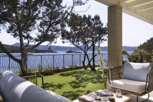 eine Veranda mit einem Stuhl und einem Tisch sowie Blick auf das Wasser in der Unterkunft 7Pines Resort Sardinia - A Destination By Hyatt in Baja Sardinia