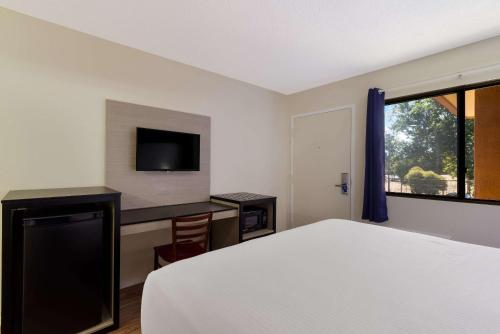 a bedroom with a bed and a desk and a television at Rodeway Inn Livermore in Livermore