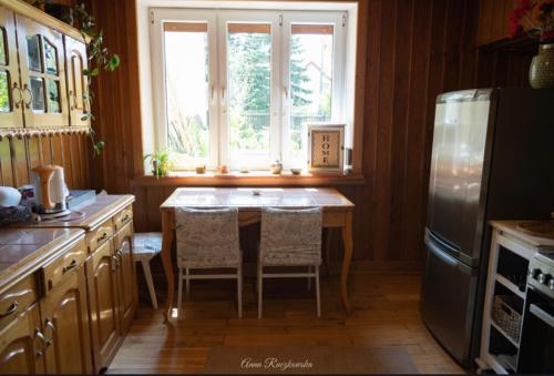 una cucina con tavolo, frigorifero e finestra di Wiejska Sielanka 