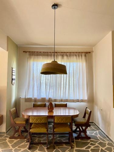 uma sala de jantar com uma mesa e uma janela em The Leaf House em Varípetron