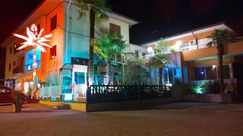 a building with palm trees on a street at night at Hotel Cubamia in Romano D'Ezzelino