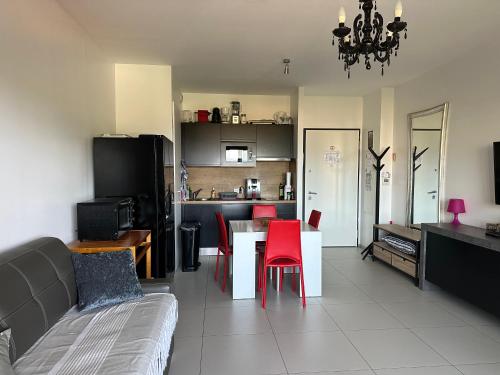 a living room with a couch and a table with red chairs at Studio T1 bis vue mer Propriano in Propriano