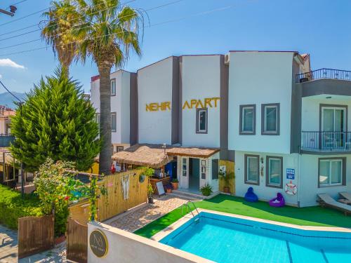 a villa with a swimming pool in front of a building at Nehir Apart Hotel in Fethiye