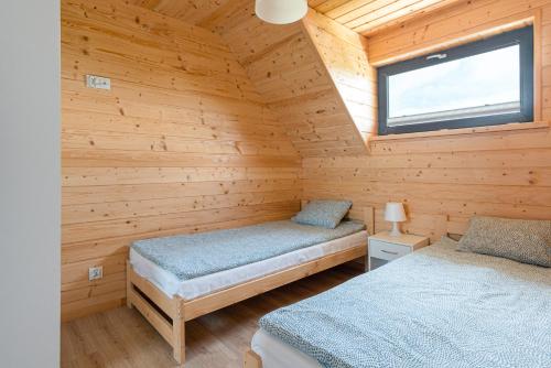 a bedroom with two beds in a wooden cabin at SIEDLISKO JANTAR Resort&Spa in Jantar