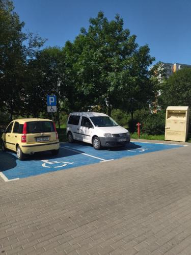two cars are parked in a parking lot at Dziesiąte Piętro in Poznań