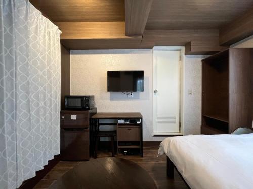 a bedroom with a bed and a desk with a microwave at Cozy inn Oyama in Tokyo