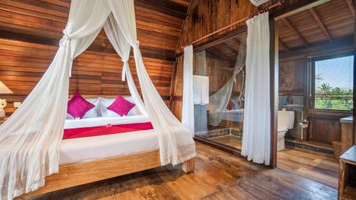 a bedroom with a bed with a mosquito net at Gayatri Retreat Ubud in Ubud