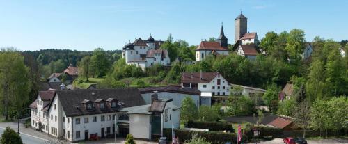 un pueblo en una colina con casas y una iglesia en Brauereigasthof Rothenbach en Aufseß