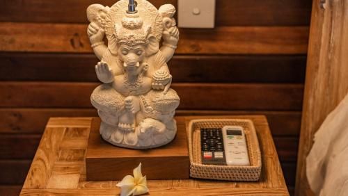 a statue of a deity on a table with a remote control at Gayatri Retreat Ubud in Ubud