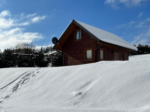 a house in the snow with footprints in front of it at Domek na Słonecznym Pagórku in Baligród