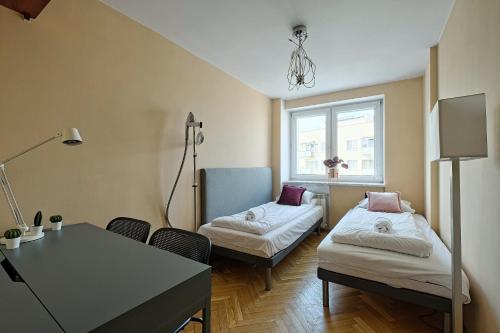 Habitación con 2 camas, mesa y ventana en 2Br Apt Balcony Tamka 17 AC, en Varsovia