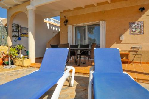 a patio with two blue chairs and a table at Sea View Family Villa with Private Pool, San Juan de los Terreros in Pulpí