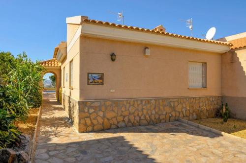 a house with a stone wall next to a driveway at Sea View Family Villa with Private Pool, San Juan de los Terreros in Pulpí