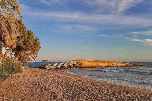 a sandy beach with a pier in the ocean at Sea View Family Villa with Private Pool, San Juan de los Terreros in Pulpí
