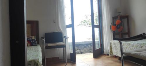 Cette chambre comprend un miroir, une chaise et une fenêtre. dans l'établissement Casa Praia Tarrafal de Monte Trigo, à Seladinha