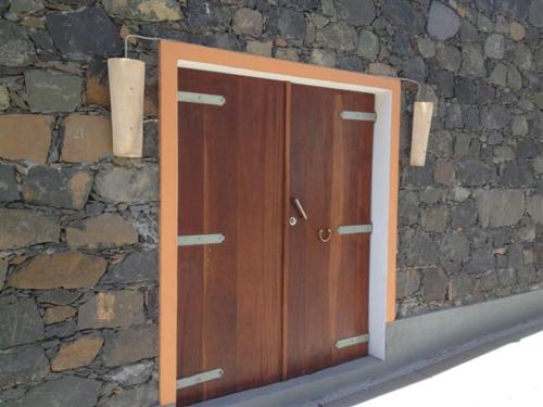 a wooden door in front of a stone wall at Casa Praia Tarrafal de Monte Trigo in Seladinha
