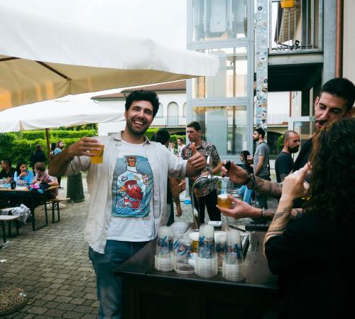 a man holding a glass of beer at a bar at Ostello La Salana in Capannori