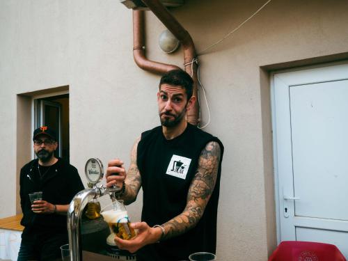 a man with tattoos on his arm holding a bottle of beer at Ostello La Salana in Capannori