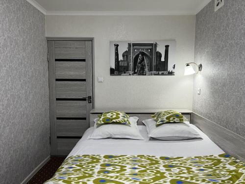 ein Schlafzimmer mit einem Bett mit zwei Kissen in der Unterkunft Status House in Fargʻona