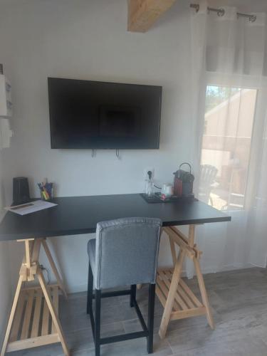 un bureau noir avec une chaise et une télévision murale dans l'établissement Chambre climatisée à 20 minutes de bordeaux, à Marcamps