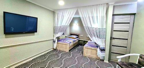 a room with two beds and a flat screen tv at Status House in Fergana