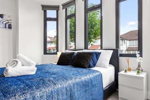 a bedroom with a blue and white bed with windows at Comfy 1BDR - 30mins to CENTRAL LDN - Parking in The Hyde