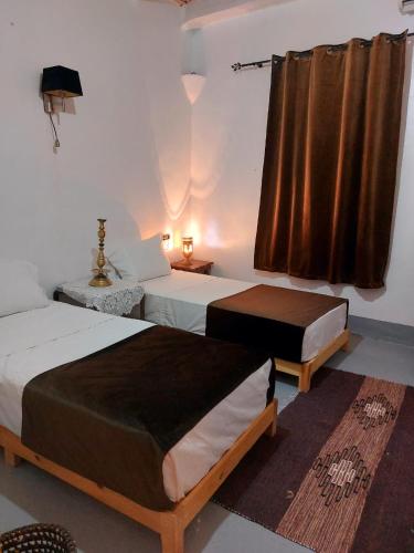 a bedroom with two beds and a window at Tizi Maison d'Hôtes in Telouet