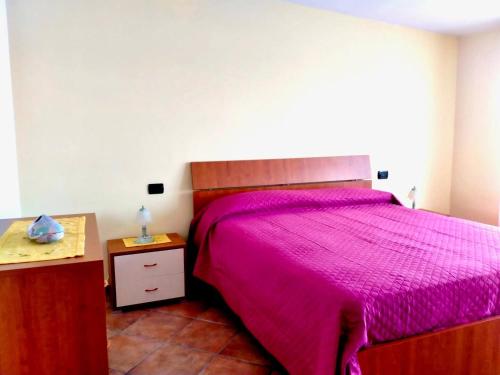 a bedroom with a bed with a pink bedspread at I due ulivi in Arzano