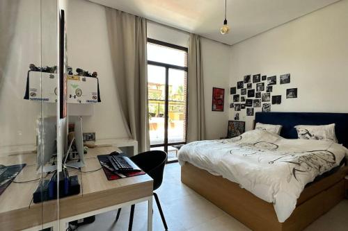 Schlafzimmer mit einem Bett und einem Schreibtisch mit einem Computer in der Unterkunft Jolie villa Front de Golf in Marrakesch