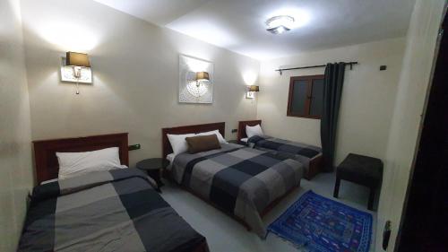 a bedroom with two beds and a table and chairs at Tizi Maison d'Hôtes in Telouet