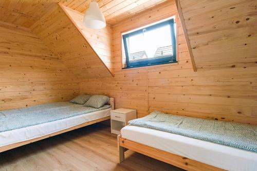 a bedroom with two beds in a wooden cabin at Osada Jantar 3 in Jantar