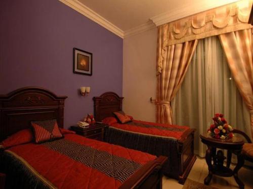 RAMEE SUITE 3 في المنامة: غرفة نوم بسريرين مع شراشف حمراء