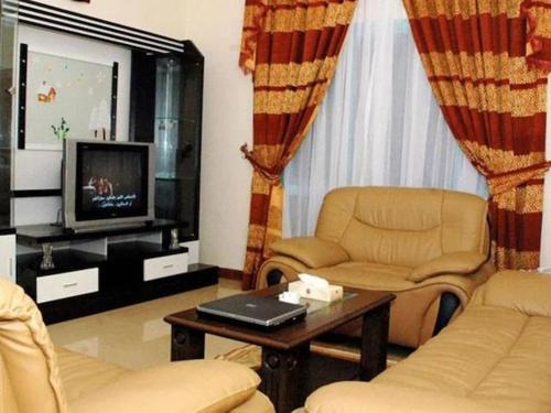 RAMEE SUITE 3 في المنامة: غرفة معيشة مع كرسيين وتلفزيون