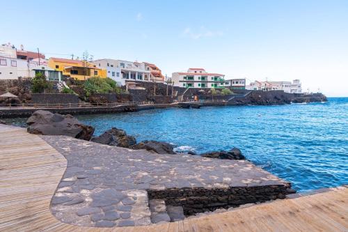 a walkway next to a body of water with buildings at La Casita a 60 pasos del mar in Tamaduste