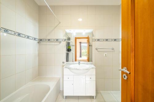 a white bathroom with a tub and a sink at Vila Sol in Prazeres