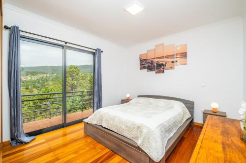 a bedroom with a bed and a large window at Vila Sol in Prazeres
