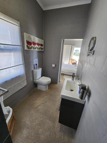 a bathroom with a white toilet and a sink at Mirage-Beach Apartment in St Helena Bay
